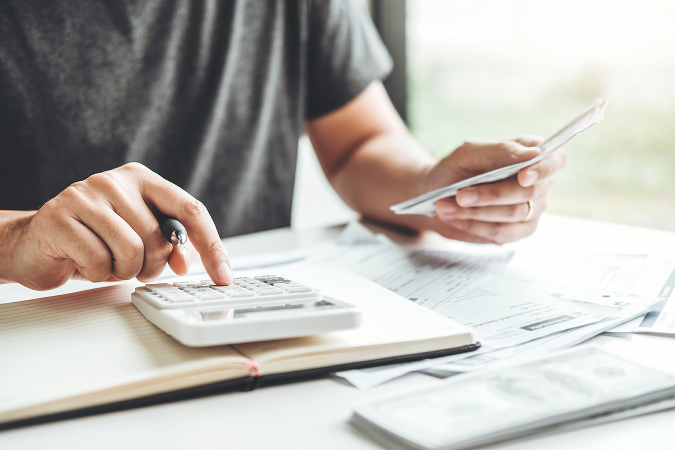 Man using calculator Accounting Calculating Cost Economic bills with money stack step growing growth saving money in home , finance concept Man using calculator Accounting Calculating Cost Economic bills with money stack step growing growth saving money in home , finance concept